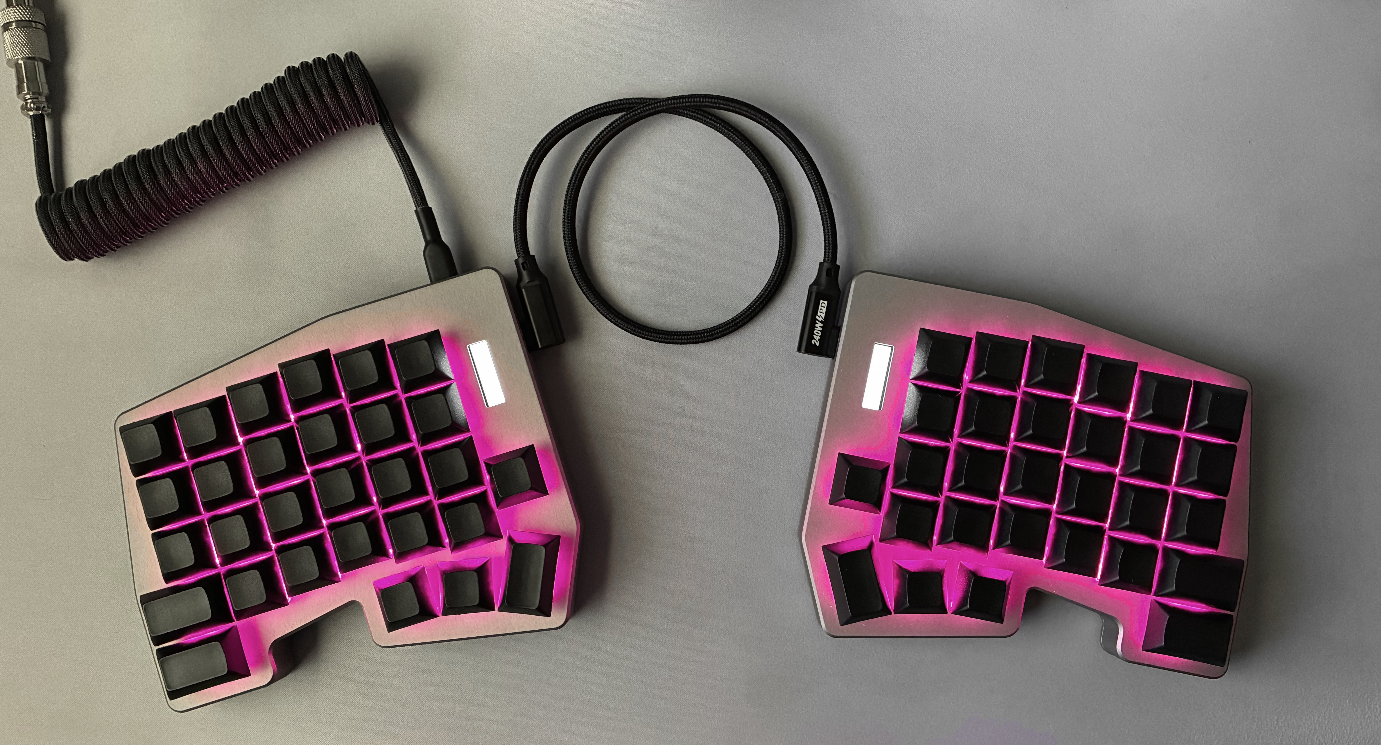 Both halves of the Hyperboard keyboard, lit with pink underglow