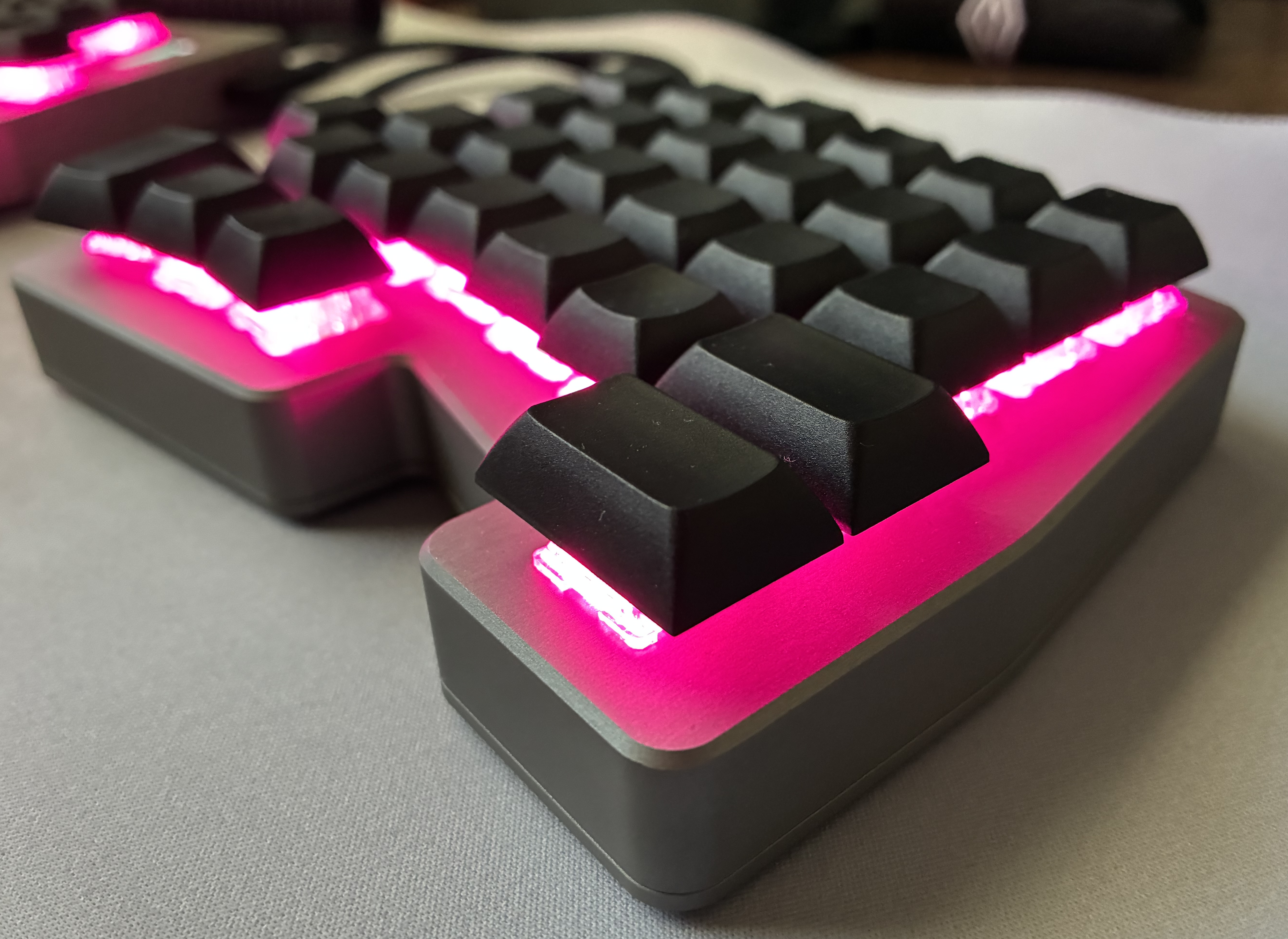 Close-up of the Hyperboard's left half, showing the machined case and backlit keycaps